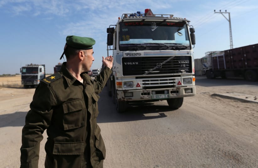 A member of the security forces of the Palestinian Authority gestures as a truck carrying goods arrives at Kerem Shalom crossing in the southern Gaza Strip November 7, 2017.  (photo credit: REUTERS/IBRAHEEM ABU MUSTAFA)
