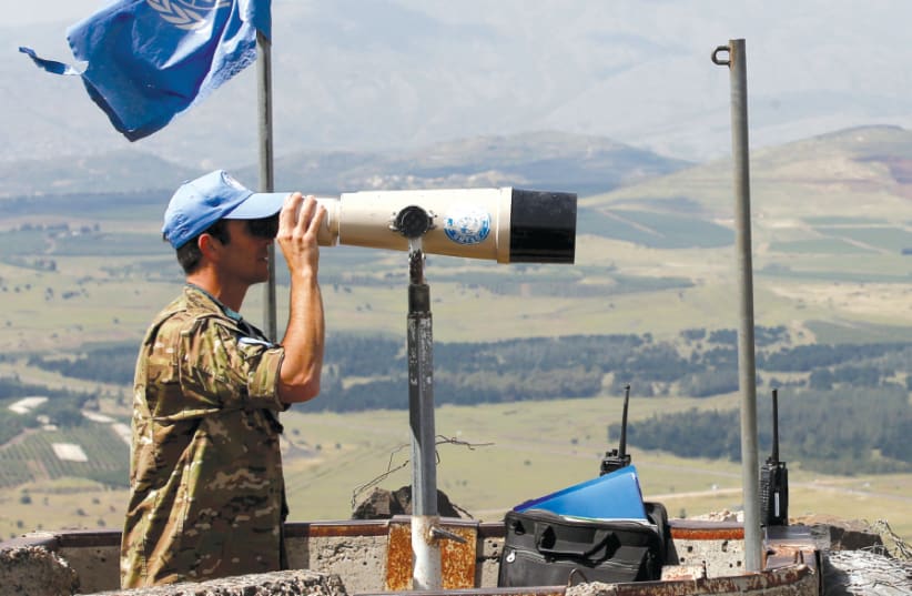 A UNITED NATIONS observer keeps watch over the Syrian border from the Golan Heights, May 2018 (photo credit: REUTERS)