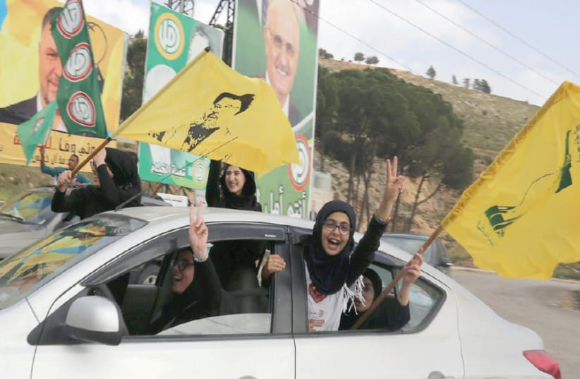 HEZBOLLAH SUPPORTERS gesture out of a car window in Marjayoun, Lebanon, on May 7, 2018 (photo credit: REUTERS)