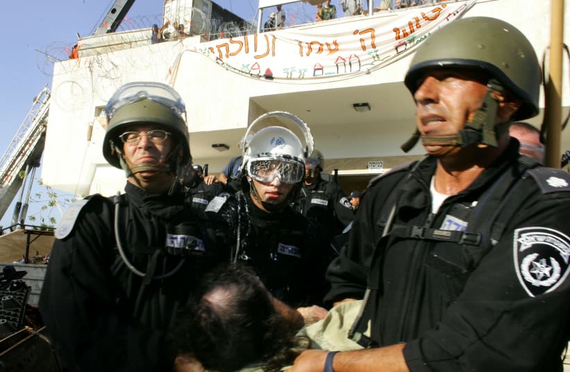Israeli security forces drag a protester opposing Israel's disengagement plan from Gaza, in the Jewish settlement of Kfar Darom in the southern Gaza Strip, August 18, 2005 (photo credit: REUTERS)