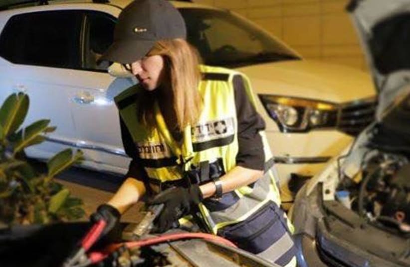 A female volunteer from Yedidim helps reset a car in the Tel Aviv suburb of Ramat Aviv (photo credit: YEDIDIM ISRAEL)