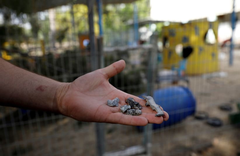A man holds shrapnel from mortar shells fired from the Gaza Strip that landed near a kindergarten, in a Kibbutz on the Israeli side of the Israeli-Gaza border, May 29, 2018 (photo credit: AMIR COHEN/REUTERS)