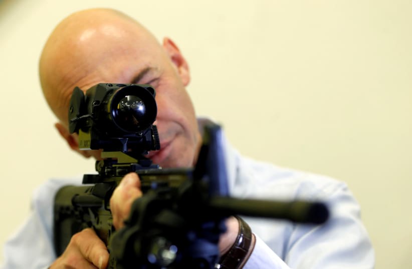 An employee looks through an infrared scope on a weapon at a preview presentation at Elbit Systems, Israel's biggest publicly listed defense firm (photo credit: REUTERS/BAZ RATNER)