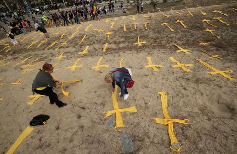 Catalan separatist supporters remove yellow crosses after a protest to demand the release of jailed Catalonian politicians, at Mataro's beach, north of Barcelona, Spain May 27, 2018 (photo credit: ALBERT GEA/ REUTERS)