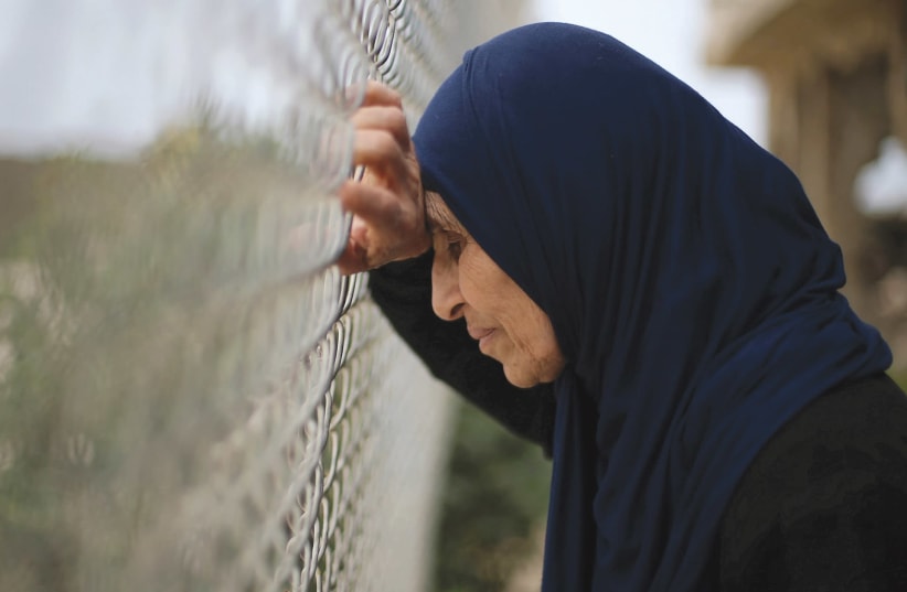 A Palestinian woman leans on a fence (photo credit: REUTERS)