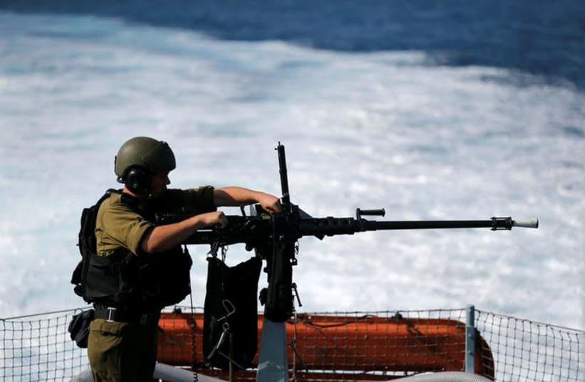 An Israeli soldier from the navy loads a machine gun as he takes part in a drill practicing the defense of Israel's borders, in the Mediterranean Sea, off the coast of Ashdod, southern Israel November 14, 2017. (photo credit: AMIR COHEN/REUTERS)