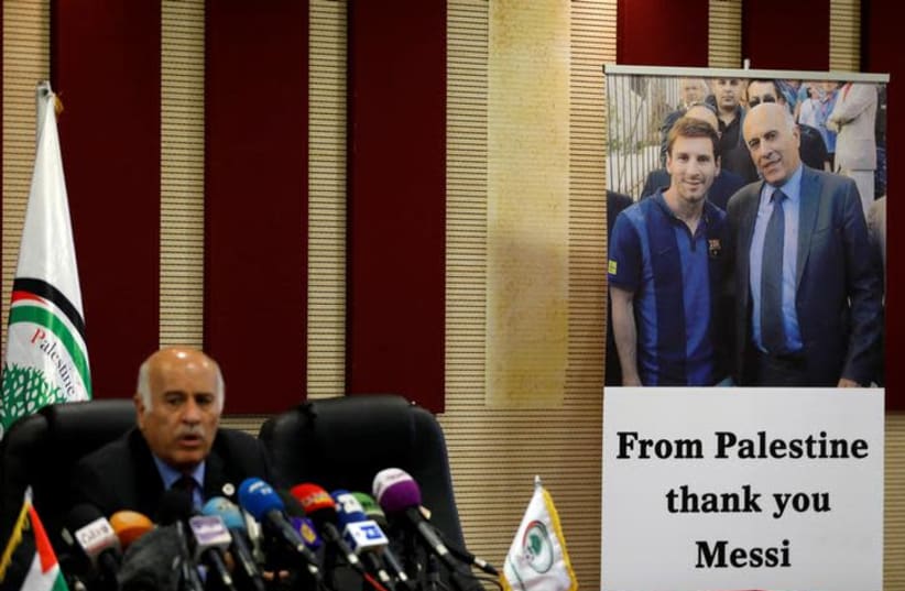 A poster of Palestinian FA chief Jibril Rajoub with Argentina's soccer player Lionel Messi is seen during Rajoub's news conference, in Ramallah in the West Bank June 6, 2018. (photo credit: REUTERS/MOHAMAD TOROKMAN)