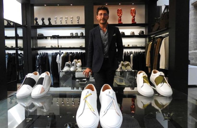 Syrian designer Daniel Essa poses with his prototype luxury sneakers displayed to be seen for online sale at a concept store in Lille, France, June 6, 2018. Picture taken June 6, 2018 (photo credit: NOEMIE OLIVE/REUTERS)