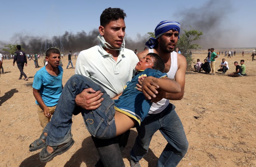 A wounded Palestinian boy is evacuated during a protest marking al-Quds Day, (Jerusalem Day), at the Israel-Gaza border in the southern Gaza Strip June 8, 2018. (photo credit: IBRAHEEM ABU MUSTAFA / REUTERS)