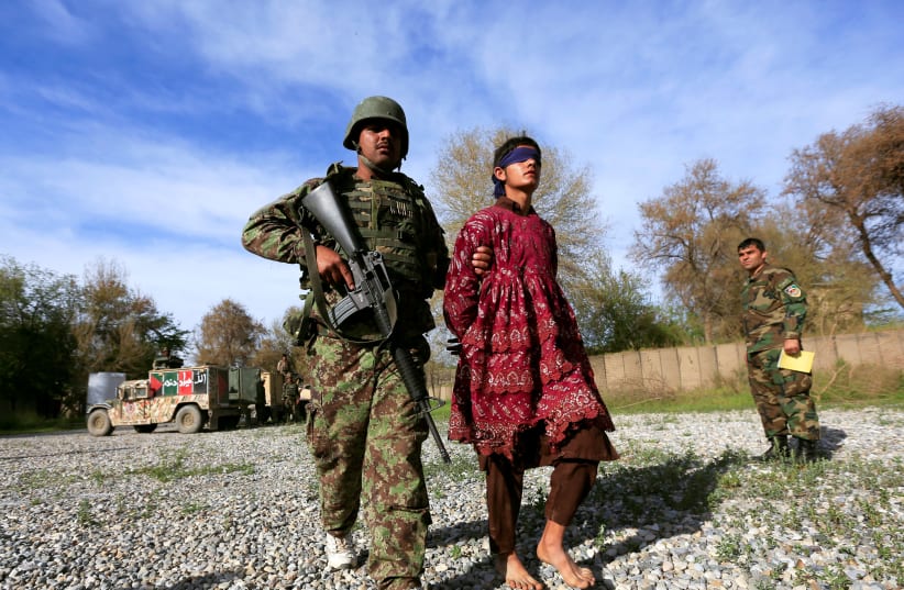 An Afghan soldier escorts a Taliban militant, who was arrested by Afghan security forces, and then presented to the media, in Jalalabad, Afghanistan March 17, 2018 (photo credit: REUTERS/PARWIZ)
