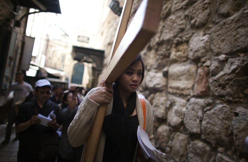 An Indonesian Christian worshipper holds a cross as she walks the Via Dolarosa on Good Friday in Jerusalem's Old City April 6, 2012. Christian worshippers retraced the route Jesus took along Via Dolorosa to his crucifixion in the Church of the Holy Sepulchre. (photo credit: DARREN WHITESIDE / REUTERS)