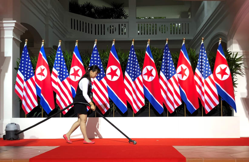 A worker vacuums the stage at the spot where U.S. President Donald Trump and North Korea's leader Kim Jong Un are expected to meet and shake hands for the first time at the start of their summit at the Capella Hotel on Singapore's resort island of Sentosa in Singapore June 12, 2018. (photo credit: JONATHAN ERNST / REUTERS)