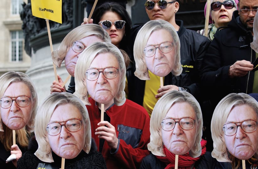 ACTIVISTS WEAR masks depicting the face of Jean-Marie Le Pen, the founder of the French far-right National Front, with the hair of current party leader, his daughter Marine Le Pen, during a demonstration last year. (photo credit: GONZALO FUENTES / REUTERS)