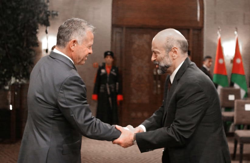 Jordan's King Abdullah II shakes hands with Prime Minister Omar al-Razzaz during a swearing-in ceremony of the new cabinet in Amman, Jordan June 14, 2018. (photo credit: REUTERS)
