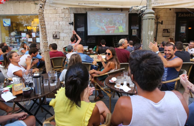 Fans sitting in a bar in Jerusalem watching the first game of the 2018 World Cup (photo credit: MARC ISRAEL SELLEM)