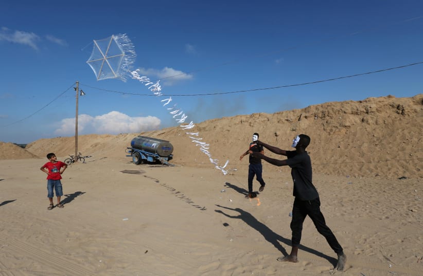 Palestinians in central Gaza fly a kite loaded with flammable material to be thrown at Israel (photo credit: IBRAHEEM ABU MUSTAFA/REUTERS)