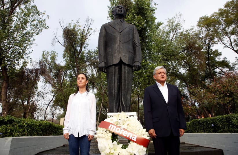 Andres Manuel Lopez Obrador, presidential candidate of the National Regeneration Movement (MORENA), offers a floral tribute to commemorate the 80th anniversary of the expropriation of Mexico's oil industry, next to Claudia Sheinbaum Pardo, candidate for Mexico City Mayor by the National Regeneration (photo credit: GINNETTE RIQUELME/ REUTERS)