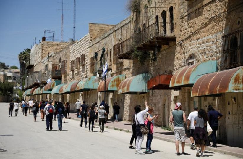 Visitors on a tour held by leftwing NGO "Breaking the Silence" walk down Shuhada street in the West Bank city of Hebron April 19, 2017 (photo credit: REUTERS/AMIR COHEN)