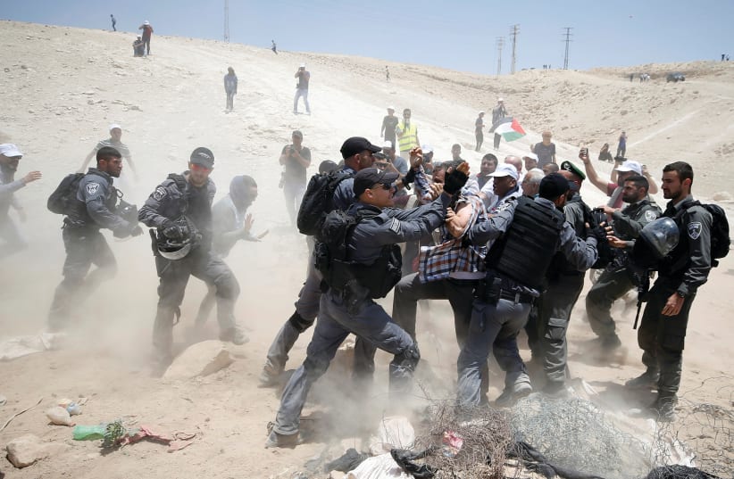 ISRAELI POLICEMEN scuffle with Palestinians in Khan al-Ahmar yesterday.  (photo credit: MOHAMAD TOROKMAN/REUTERS)