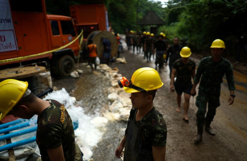 Military personnel walk in line as they prepare to enter the Tham Luang cave complex, where 12 boys and their soccer coach are trapped, in the northern province of Chiang Rai, Thailand, July 6, 2018 (photo credit: REUTERS/ATHIT PERAWONGMETHA)