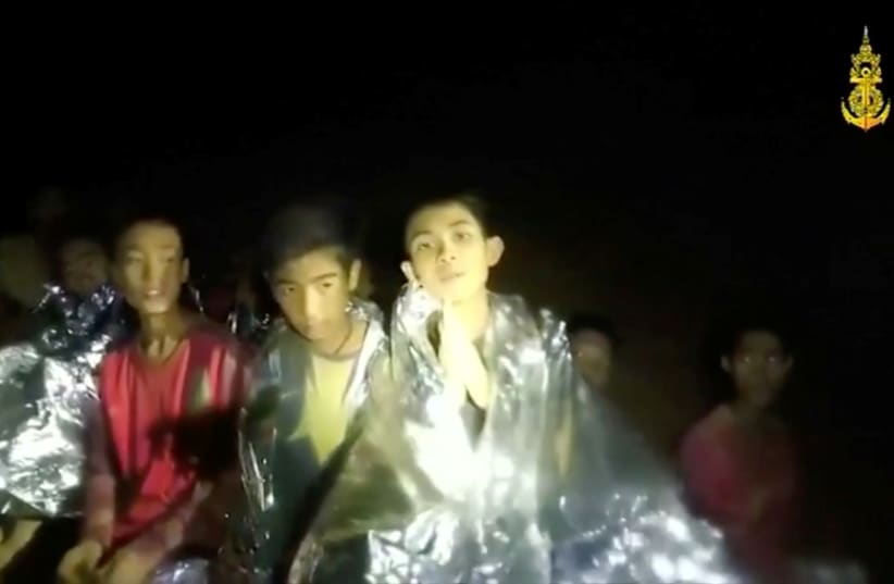 Boys trapped inside Tham Luang cave greet members of the Thai rescue team, in this still image taken from a July 3, 2018 video by Thai Navy Seal (photo credit: THAI NAVY SEAL/HANDOUT VIA REUTERS TV)