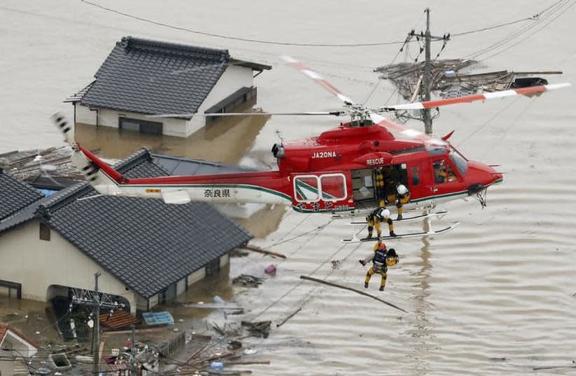 An aerial view shows a local resident being rescued from a submerged house by rescue workers using helicopter at a flooded area in Kurashiki, southern Japan, in this photo taken by Kyodo July 7, 2018 (photo credit: KYODO/VIA REUTERS)