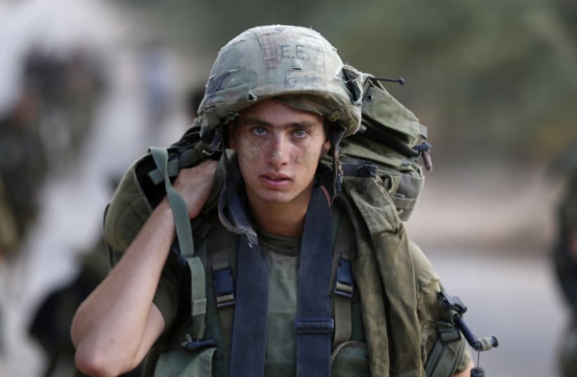 An Israeli soldier from the Nahal Brigade carries equipment after returning to Israel from Gaza August 5, 2014 (photo credit: REUTERS/BAZ RATNER)