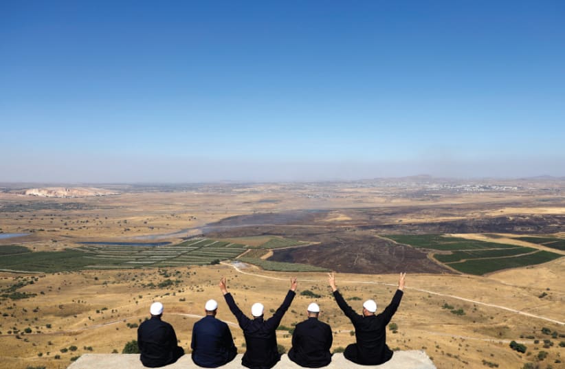 Israeli Druze watch the Syrian side of the Israel- Syria border on the Golan Heights on July 7, 2018 (photo credit: RONEN ZVULUN/REUTERS)