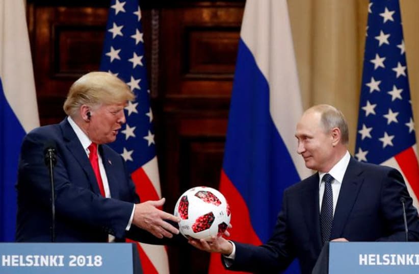 U.S. President Donald Trump receives a football from Russian President Vladimir Putin as they hold a joint news conference after their meeting in Helsinki, Finland July 16, 2018 (photo credit: GRIGORY DUKOR / REUTERS)