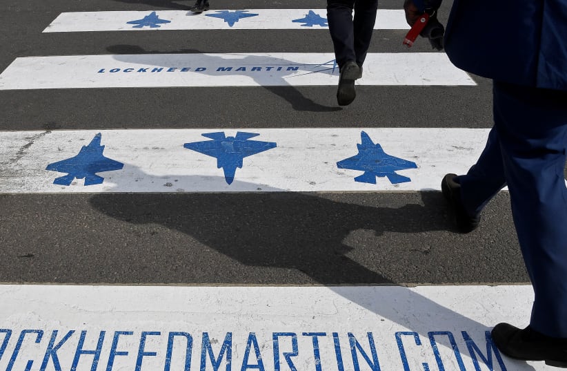 Trade visitors are seen walking over a road crossing covered with Lockheed Martin branding at Farnborough International Airshow in Farnborough, Britain, July 17, 2018. (photo credit: TOBY MELVILLE/REUTERS)