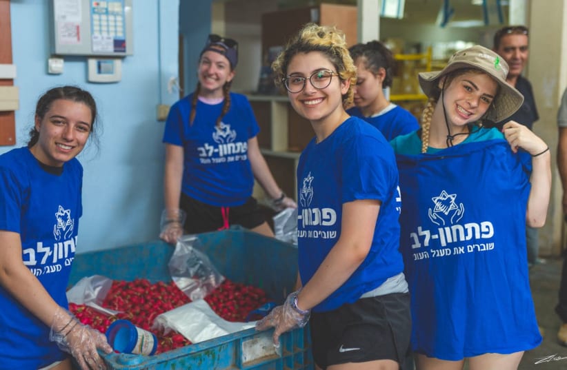 Delegation participants from the Detroit-based Sue & Alan Jay Kaufman Family Teen Mission to Israel help pack boxes of food at the Pitchon Lev aid center on Tuesday, July 10 (photo credit: ZIV TOLEDANO)