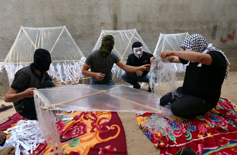 Palestinians prepare kites loaded with flammable material to be thrown at the Israeli side, near the Israel-Gaza border in the central Gaza Strip in June.. (photo credit: IBRAHEEM ABU MUSTAFA / REUTERS)
