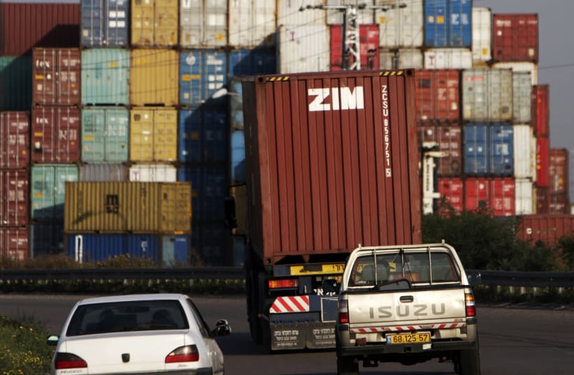 Cars drive behind a truck transporting a Zim container just outside Israel's port of Ashdod February 23, 2012 (photo credit: AMIR COHEN/REUTERS)