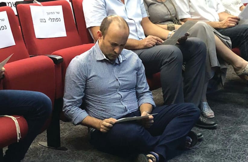 Education and Diaspora Affairs Minister Naftali Bennett sits on the floor to read the Book of Lamentations at an event commemorating Tisha Be’av in Shoham on Saturday night. (photo credit: Courtesy)
