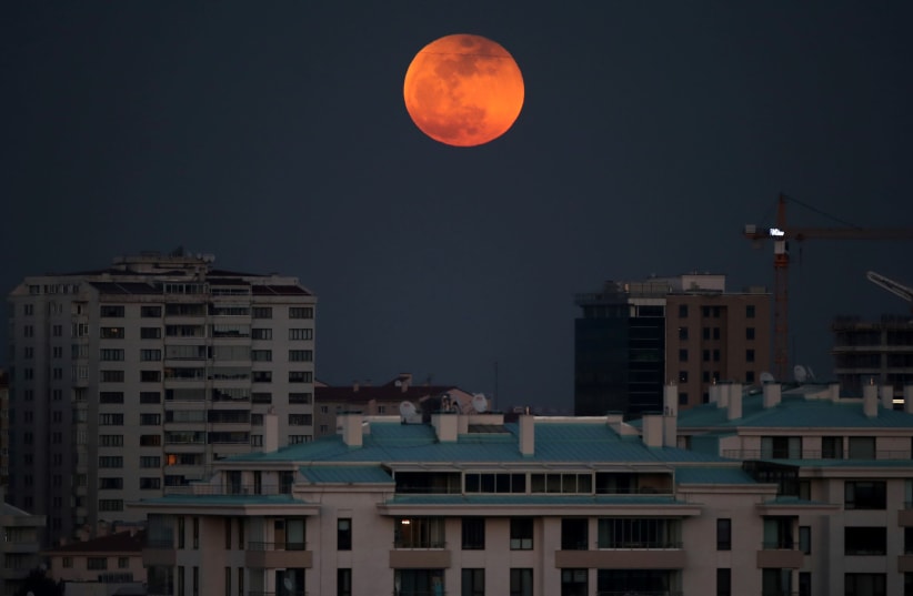 A super blue blood moon rises over an apartment block during a lunar eclipse in Ankara, Turkey, January 31, 2018. (photo credit: UMIT BEKTAS / REUTERS)