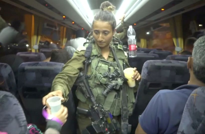 An Israeli solider hands out water on a bus, during the Syria Civil Defence, also known as the White Helmets, extraction from the Golan Heights (photo credit: IDF SPOKESPERSON UNIT VIA REUTERS)