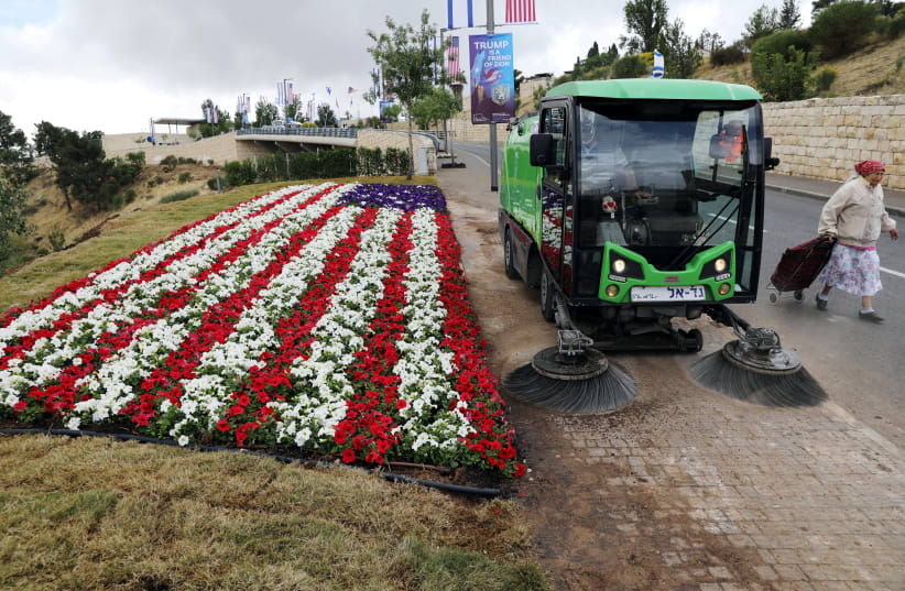 A street sweeper cleans sidewalk next to a flower bed in shape of U.S. flag, near location of new U.S. embassy in Jerusalem, 2018. (photo credit: AMMAR AWAD/REUTERS)