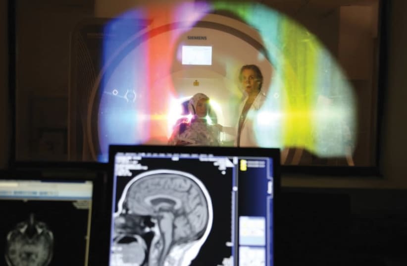 PROF. TALMA HENDLER, founding director of the Sagol Brain Institute in Tel Aviv, examines a patient with the hospital’s groundbreaking brain imaging technology (photo credit: SOURASKY MEDICAL CENTER)