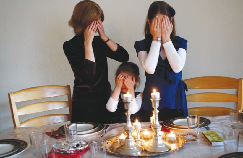 MEMBERS OF the Nogradi family light candles for Shabbat in their home in Budapest (photo credit: REUTERS)