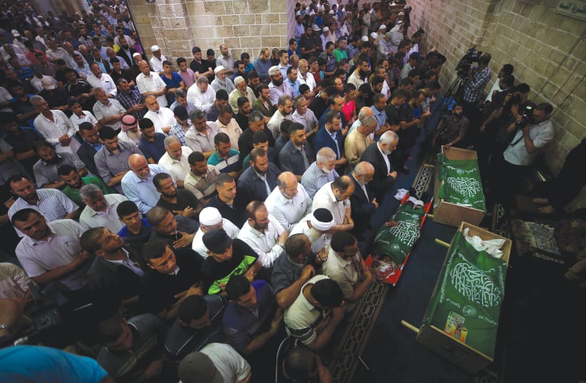 PALESTINIANS PRAY yesterday next to the bodies of Hamas terrorists killed by Israeli tank fire, during their funeral at a mosque in Gaza City. (photo credit: REUTERS/MOHAMMED SALEM)