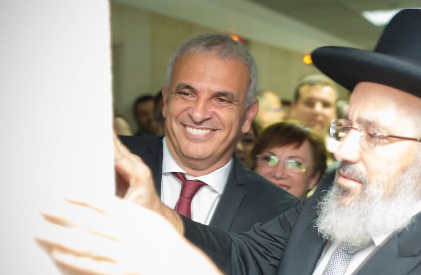 Finance Minister Moshe Kahlon affixes a mezuza at Kulanu party's new Tel Aviv headquarters, help of Or Yehuda chief rabbi Tzion Cohen. (photo credit: ELAD MALKA)