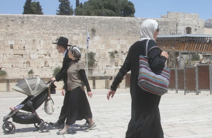 AN ARAB woman walks past a Jewish couple at the Western Wall (photo credit: MARC ISRAEL SELLEM)