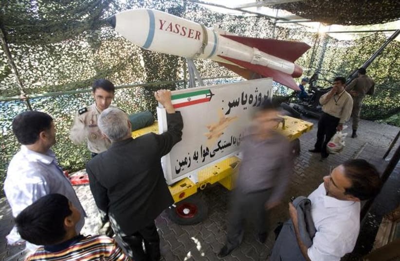 A member of Iran's army speaks with a visitor as they stand next to the Iranian Yasser ballistic bomb during a war exhibition to commemorate the anniversary of Iran-Iraq war (1980-88), in Baharestan square near the Parliament building in southern Tehran  (photo credit: REUTERS/MORTEZA NIKOUBAZL)
