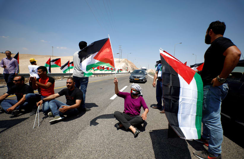 Demonstrator holds Palestinian flag during support rally of Khan al-Ahmar residents in West Bank, 2018 (photo credit: MOHAMAD TOROKMAN/REUTERS)