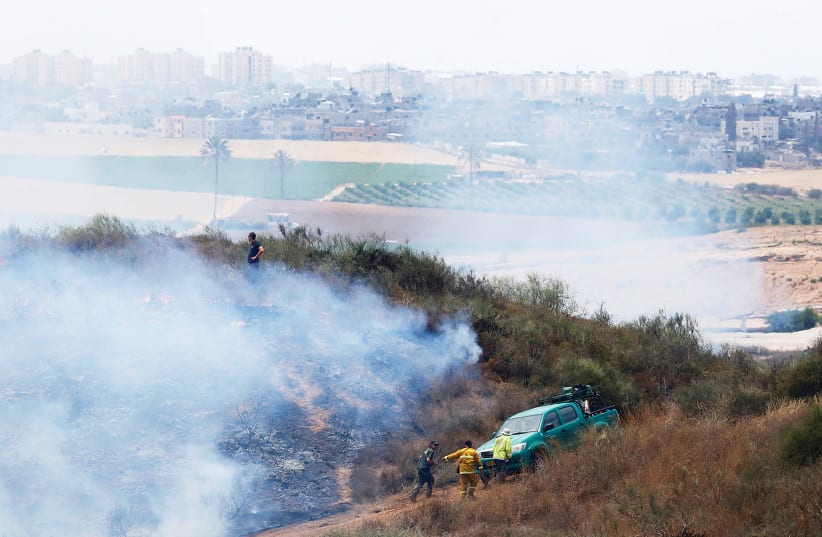 People are seen near Kibbutz Nir Am during a fire in an area where Palestinians in Gaza have been causing blazes by flying kites and balloons loaded with flammable materials.  (photo credit: AMIR COHEN/REUTERS)