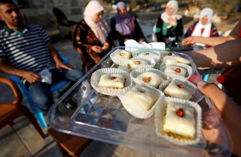 Relatives of Rashida Tlaib, who is set to become the first Muslim woman to join the U.S. Congress, distribute sweets as they celebrate her election victory, in the village of Beit Ur al-Fauqa in the West Bank August 8, 2018. (photo credit: MOHAMAD TOROKMAN/REUTERS)