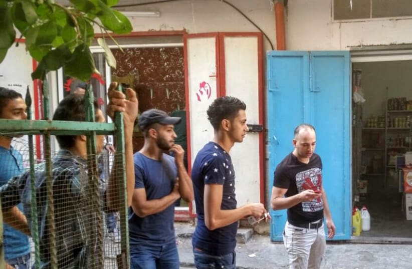 Za'bour in a black T-shirt holds his cell phone next to a group of young men from Balata refugee camp (photo credit: KHALED ABU-TOAMEH)