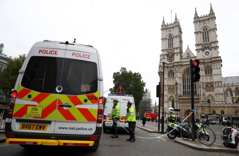 Police officers stand at a cordon after a car crashed outside the Houses of Parliament in Westminster, London, Britain, August 14, 2018 (photo credit: HANNAH MCKAY/ REUTERS)
