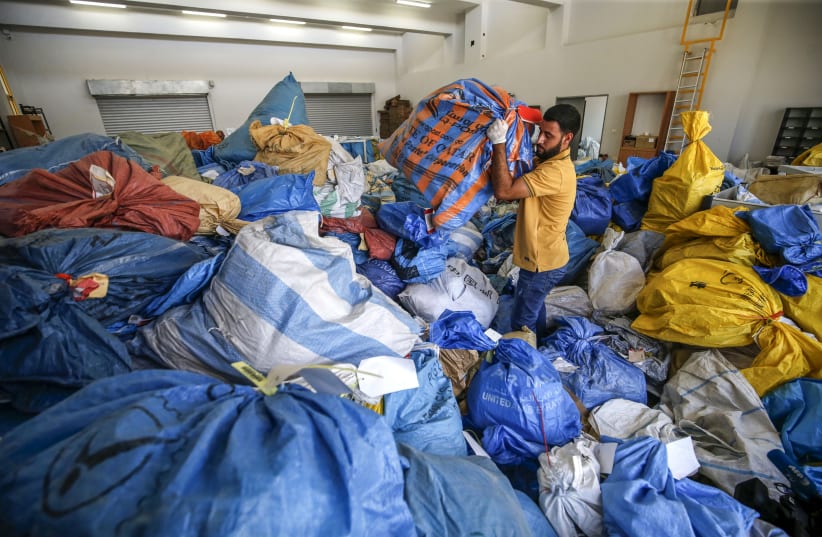 A Palestinian postal worker sifts through sacks of previously undelivered mail dating as far back as 2010, which has been withheld by Israel, at the central international exchange post office in the city of Jericho in the occupied West Bank on August 14, 2018. For up to eight years, Israel had preve (photo credit: ABBAS MOMANI / AFP)