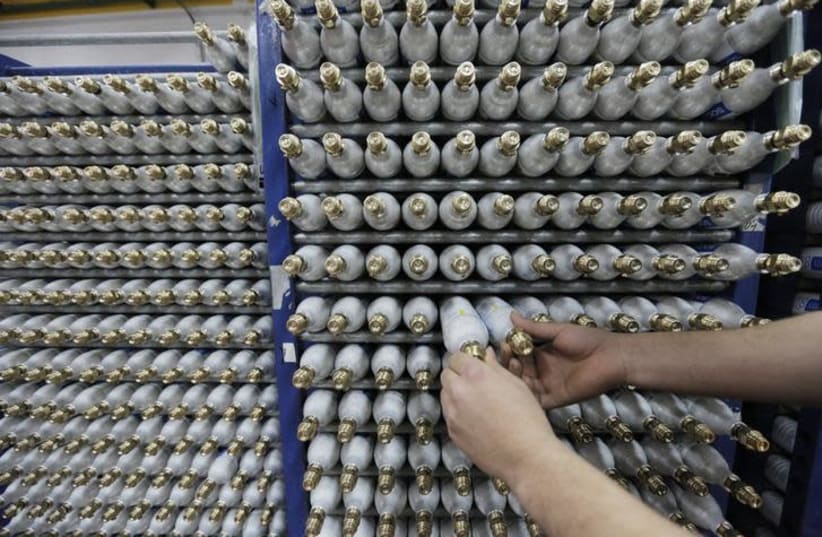 An employee sorts carbonator bottles while working at the SodaStream factory in the West Bank (photo credit: REUTERS/AMMAR AWAD)